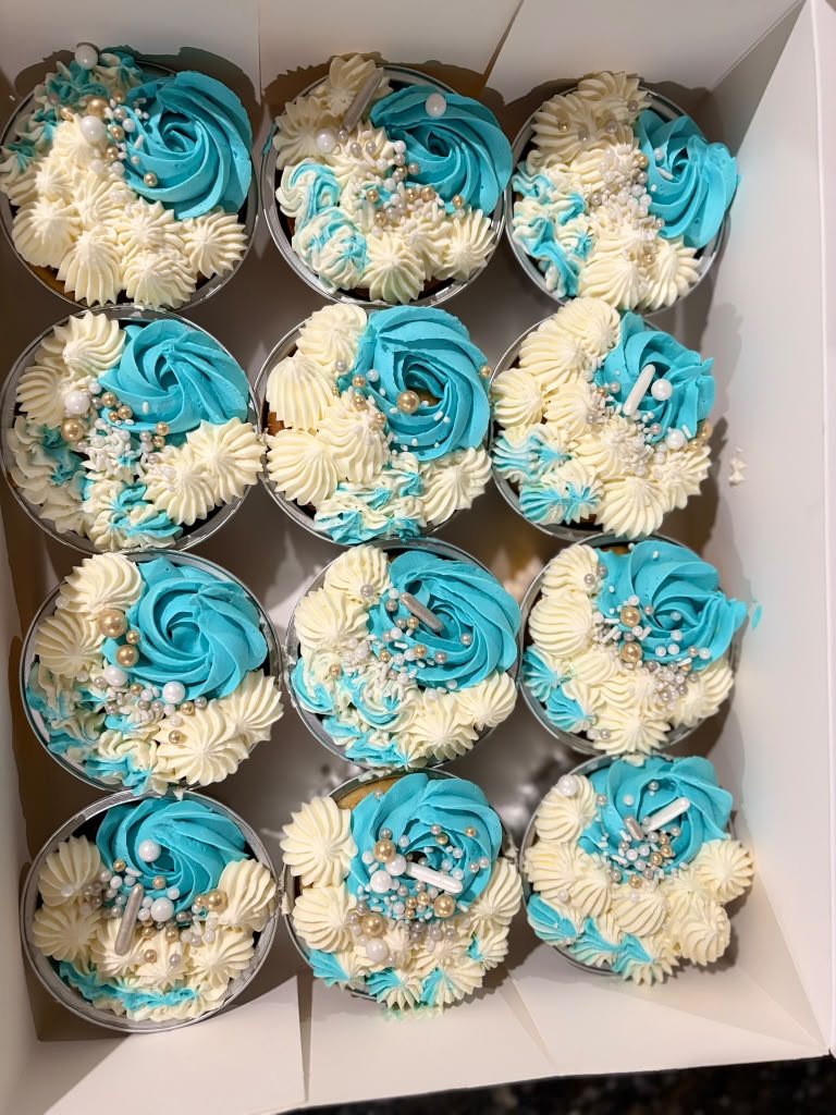 Blue and cream cupcakes arranged in a gift box